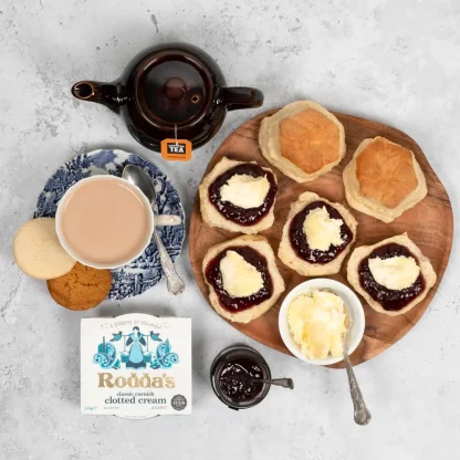 Cream tea served on wooden board next to teapot