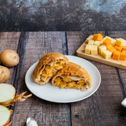 Cheese and onion pasty sliced open on plate
