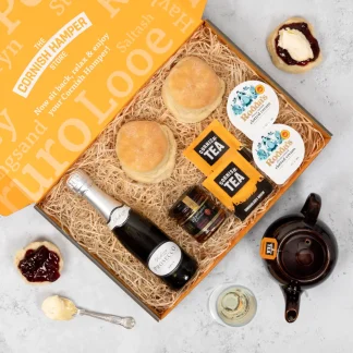 Cornish Cream Tea & Prosecco Postal Hamper beautifully laid out on a bed of straw. The box contains two Cornish scones, 2 40g pots of Rodda's clotted cream, 2 Cornish tea bags, a jar of strawberry jam and a miniature bottle of Prosecco