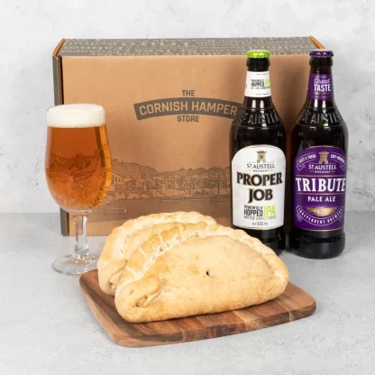 Two freshy baked Cornish Pasties rest beside a bottle of Tribute Pale Ale and a bottle of Proper Job