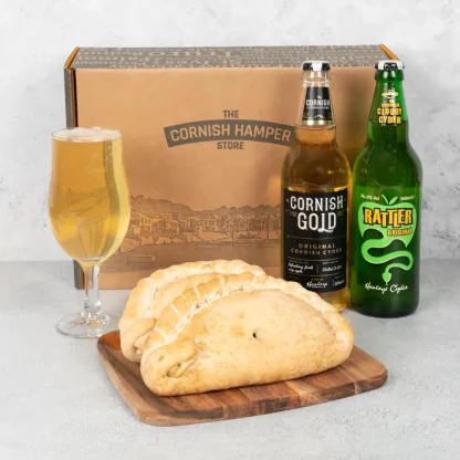 Two freshly baked Cornish pasties rest beside a bottle of Rattler original and a bottle of Cornish Gold