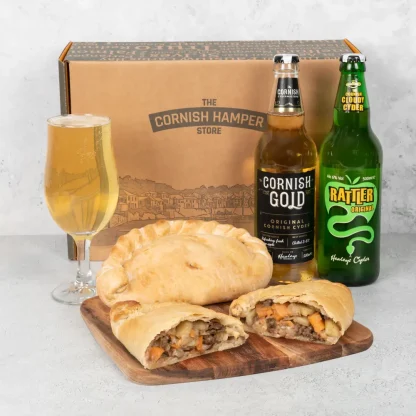 Two freshly baked Cornish pasties rest beside a bottle of Rattler original and a bottle of Cornish Gold