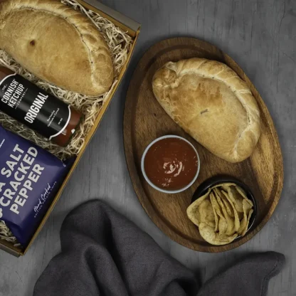 Traditional cornish pasty presented with bowl of ketchup and sea salt and cracked pepper crisps