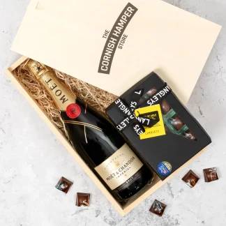 The wooden gift box is filled with langleys chocolate selection box and Moet champagne on a bed of straw