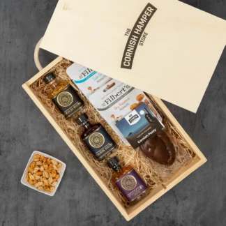 Rosemullion Rum Gift Set laid out on a bed of hamper straw. Contains miniature rum selection, peanuts and chocolate pasty
