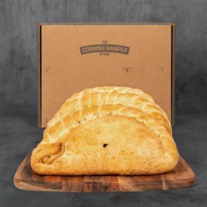 Trio of Cornish Pasties presented in a row in front of a Cornish Hamper box for Father's Day
