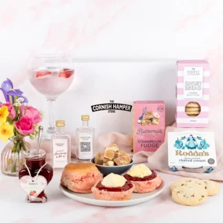 The Gin and Goodies Hamper displaying plate of pink scones topped with jam and cream surrounded by glass of gin and tonic and beautiful pink and white themed Cornish produce