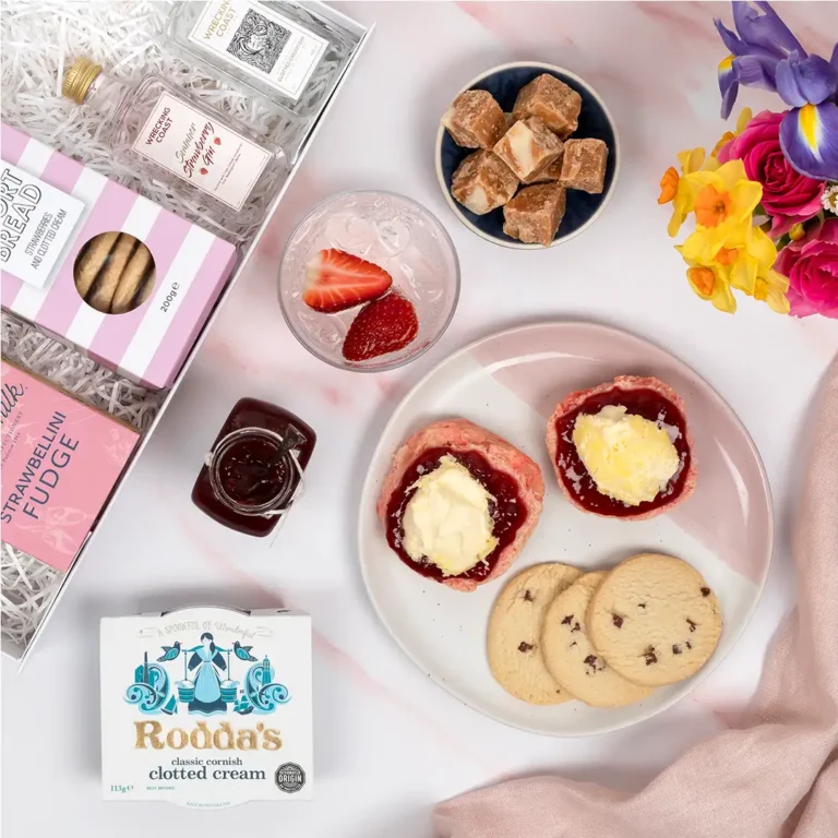 Birds eye view of Gin and Goodies hamper showing glass of gin and tonic next to plate of jam and cream topped pink scones