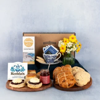 The Easter Cream Tea Hamper displaying scones topped with jam and clotted cream next to hot cross buns and hevva buns